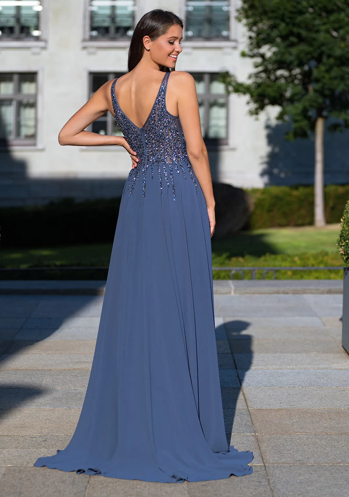 Frau in einem Abendkleid aus Chiffon und mit Pailletten-Oberteil in der Farbe Vintage-Indigo, Rückenansicht